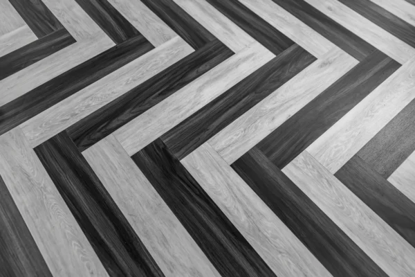 Herringbone pattern flooring in alternating light and dark wood planks creating diagonal chevron design.