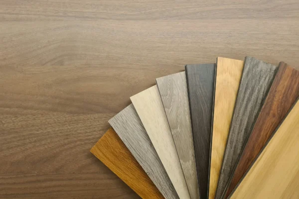 Wood flooring samples in various finishes displayed in a fan arrangement on a wooden surface.