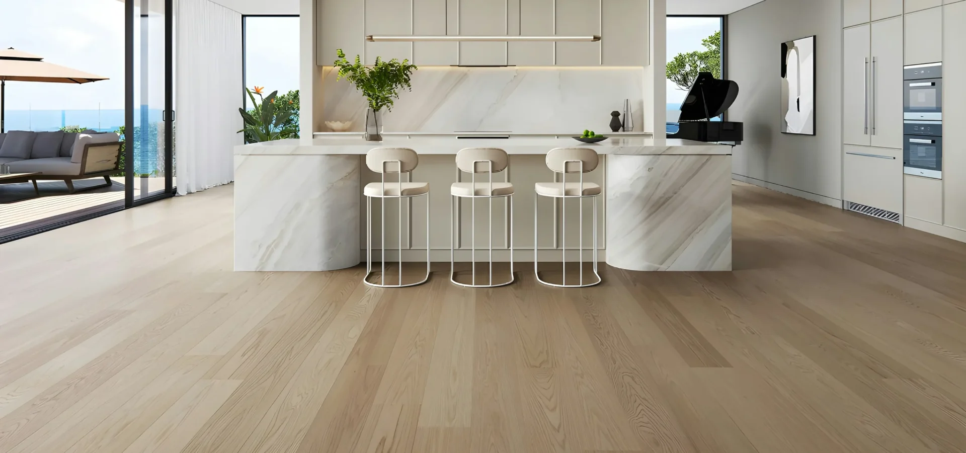 Modern luxury kitchen with marble island, white cabinetry, three bar stools, wooden flooring, and expansive windows overlooking ocean views.