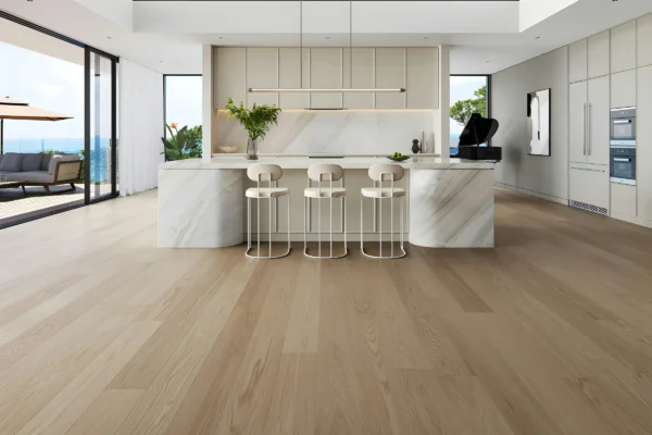 Modern luxury kitchen with marble island, white cabinetry, three bar stools, wooden flooring, and expansive windows overlooking ocean views.
