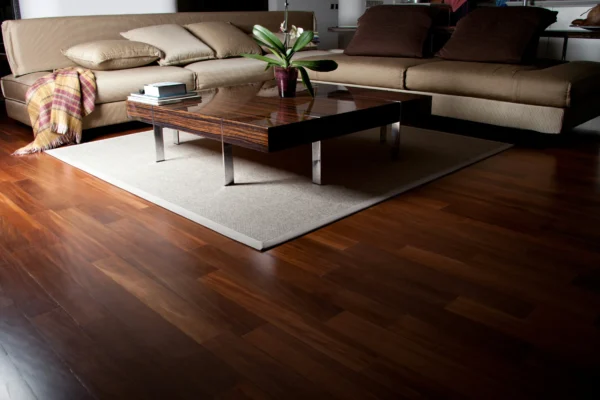 Modern living room with beige sectional sofa, dark wood coffee table, potted orchid, and polished hardwood flooring.